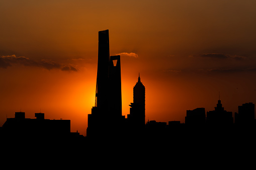 A beautiful shot of an orange sun setting near modern buildings