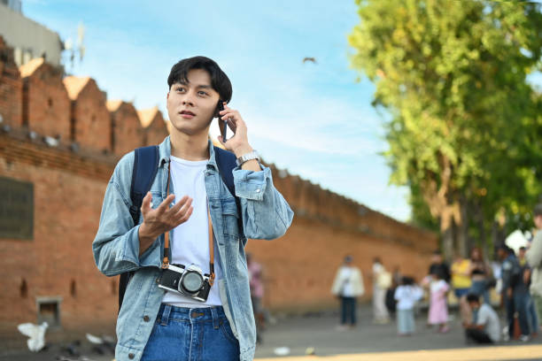 istock Image of male traveller talking on mobile phone while standing at Tha Phae Gate is a old city ancient wall in Chiang Mai northern Thailand. 1455679843