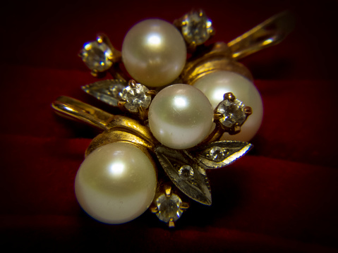 A closeup of a broche with pearls