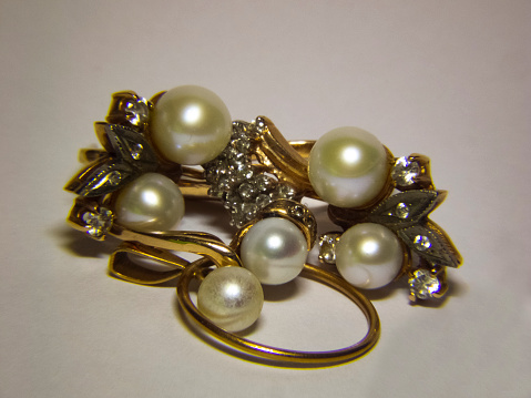 A closeup of a broche with pearls