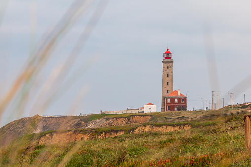 A closeup shot of a lighthouse with a greenfield around it