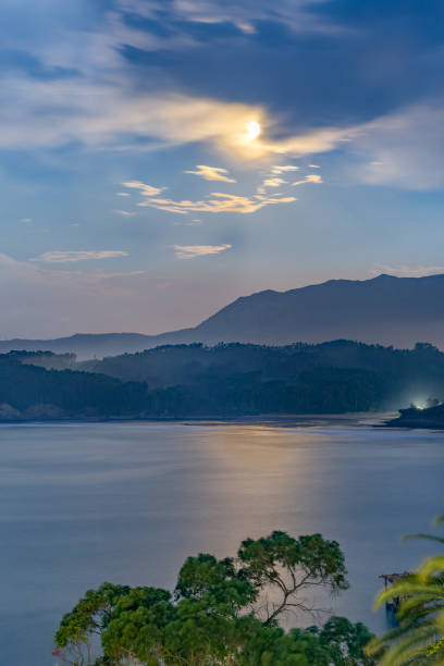 istock Long exposure night image of sea, forest and mountain illuminated by moonlight between clouds 1455686603