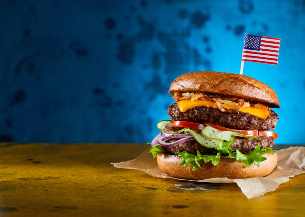 istock Delicious double burger with beef cutlets and fresh vegetables served on parchment paper 1455686909