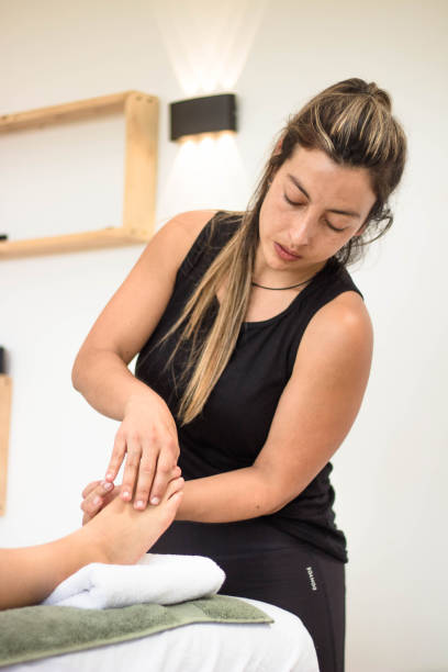 istock Hispanic professional female masseur massaging her client's foot 1455687219