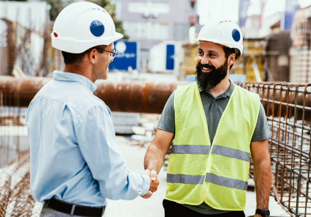 istock Engineers on construction site. Manager and contractor shaking hands and smiling 1455688533