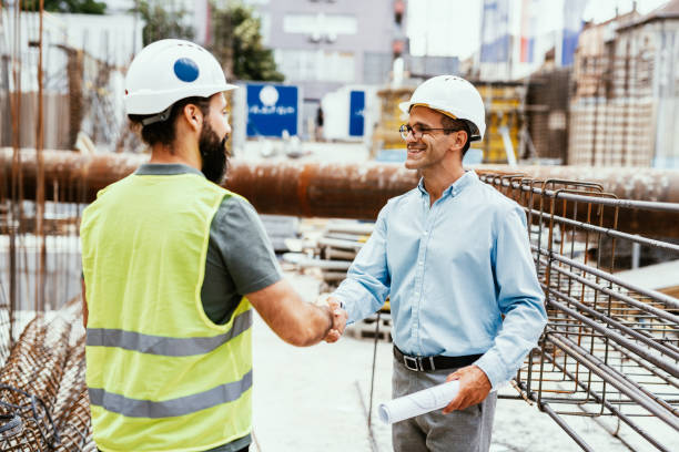 Engineers on construction site. Manager and contractor shaking hands and smiling