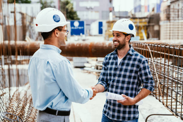 istock Engineers on construction site. Manager and contractor shaking hands and smiling 1455689529