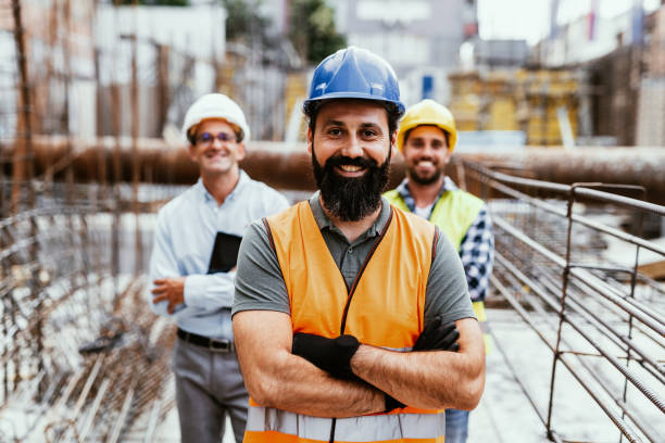 Engineers on construction site, looking at camera and smiling. Employment in housing and real estate sector
