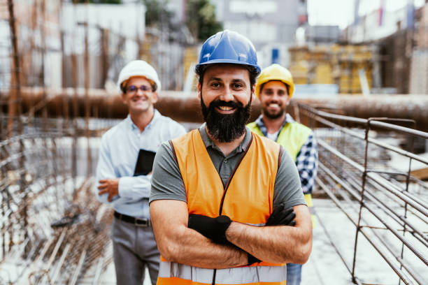 Engineers on construction site, looking at camera and smiling. Employment in housing and real estate sector stock photo