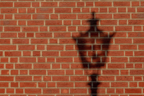 A vintage street light's shadow on a brick wall