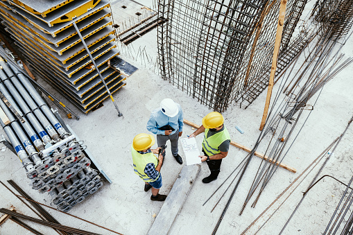 Ingenieros irreconocibles en el sitio de construcción, vista de alto ángulo de los empleados en la industria de la construcción photo