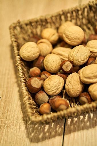 A vertical shot of a basket full of uncracked walnuts and chestnuts with a blurry background