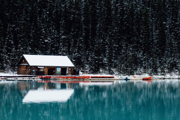 istock Small rural house on a lakeside surrounded by greenery-covered hills on a winter day 1455691041