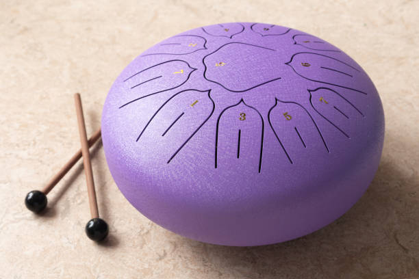 Tongue drum with drumsticks, Purple hang drum. music for relaxation and meditation Tongue drum with drumsticks, Purple hang drum. music for relaxation and meditation. tank musician stock pictures, royalty-free photos & images