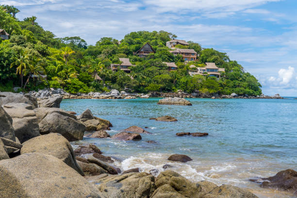 A rocky shore with blue waters at Playa de los Muertos beach at Sayulita, Nayarit, Mexico