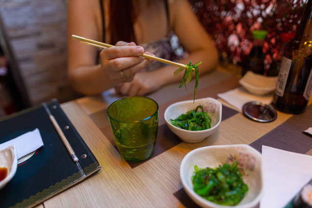 mulher caucasiana que come a salada japonesa de algas marinhas - chopsticks human hand women isolated - fotografias e filmes do acervo
