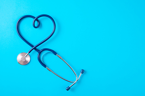 Heart Shaped stethoscope on blue background with copy space