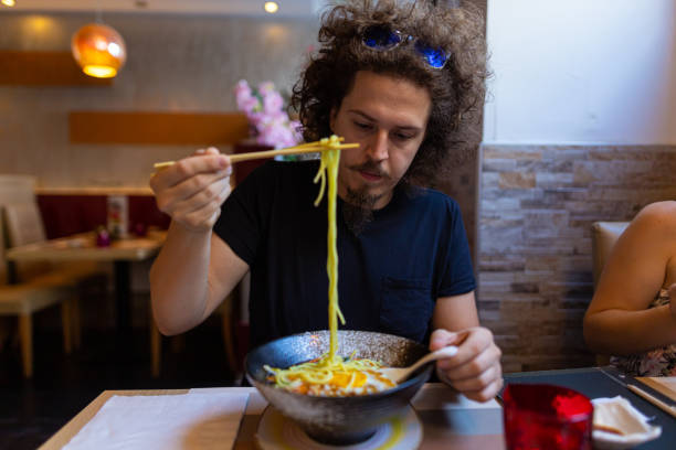 istock Caucasian man eating Japanese noodle soup with chopsticks 1455695364