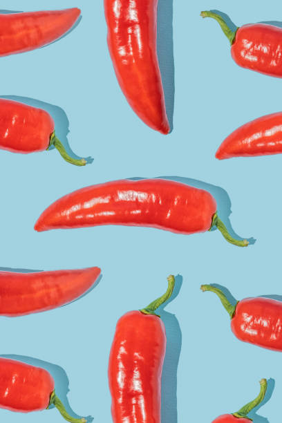 istock Pattern made of fresh red peppers on blue background. Minimal concept. 1455696759