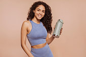 Beautiful multiracial sportswoman posing at studio holding water bottle