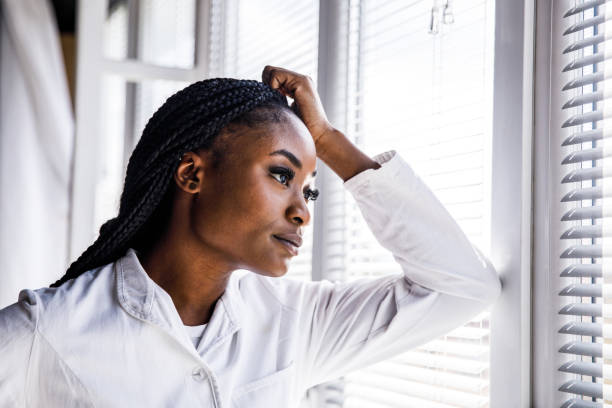 istock Female scientist leaning against the window, head in hand, taking a break from work 1455697834