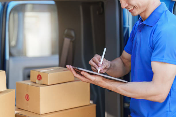 istock Asian courier with parcel and delivery logistic concept. Delivery man using digital tablet 1455698298