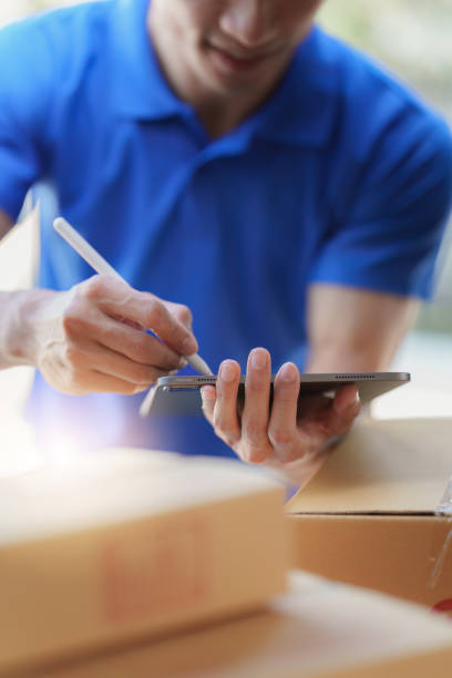 istock Asian courier with parcel and delivery logistic concept. Delivery man using digital tablet 1455698668