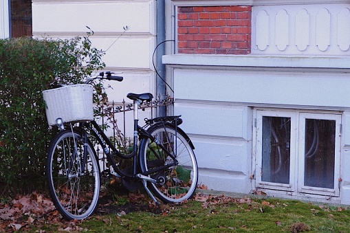 A bicycle with a basket in front of a house