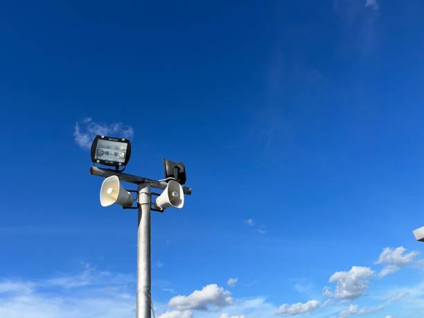 haut-parleurs et lumières suspendus à un poteau métallique avec un ciel bleu - the mall audio photos et images de collection