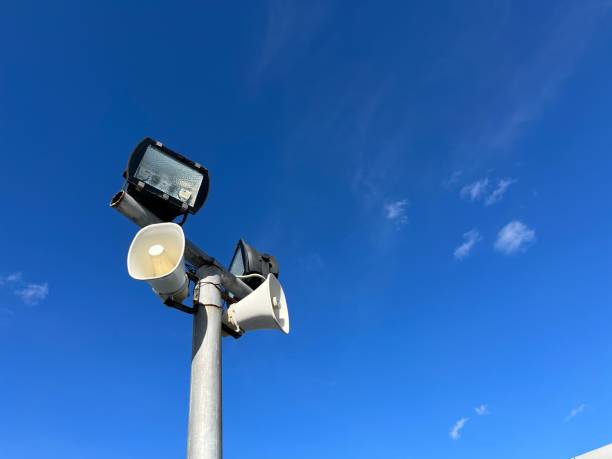 haut-parleurs et lumières suspendus à un poteau métallique avec un ciel bleu - the mall audio photos et images de collection