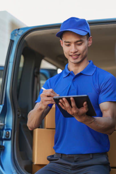 istock Asian courier with parcel and delivery logistic concept. Delivery man using digital tablet 1455699936
