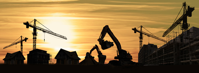 Silhouette of two Hydraulic Excavator standing at construction site during sunset time.