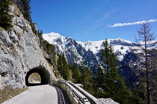 Tunnel in the Alps. View from the tunnel to the snow-covered Alps. The entrance to the tunnel on the background of snow-capped mountains. A high-altitude tunnel. A road tunnel in the mountains.