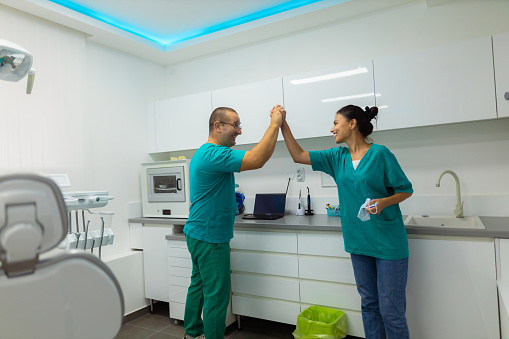 Shot of a dental doctor giving a high-five to his female assistant at the office.