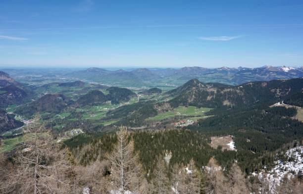Top view of the Berchtesgaden valley. Panoramic view of the valley in Berchtesgaden from the Kehlstein height. View from the Bavarian Alps down to the green valley. Winter meets spring. Snow-capped peaks of mountains and greenery below. el kehlsteinhaus (conocido en inglés como el nido del Águila) es un edificio construido por los nazis erigido sobre la cima del kehlstein, un afloramiento rocoso que se eleva sobre obersalzberg, cerca de la ciudad de berchtesgaden, en el sureste de alema