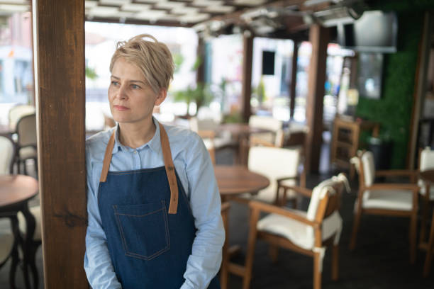 그녀의 빈 식당 한가운데에 혼란스럽게 서있는 식당 매니저의 초상화 - owner restaurant business worried 뉴스 사진 이미지