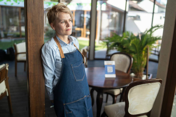 그녀의 빈 식당 한가운데에 서있는 식당 주인의 진지한 초상화 - owner restaurant business worried 뉴스 사진 이미지