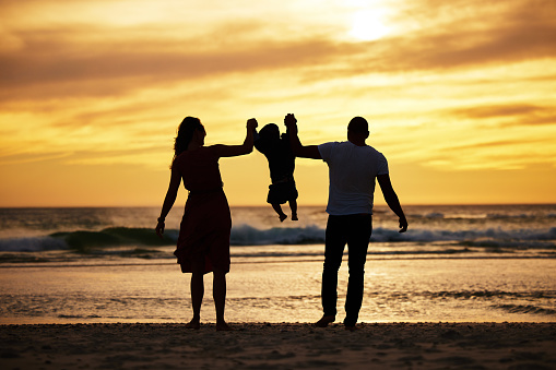 Woman with her little son in shallow sea in sunset, they are on vacation.