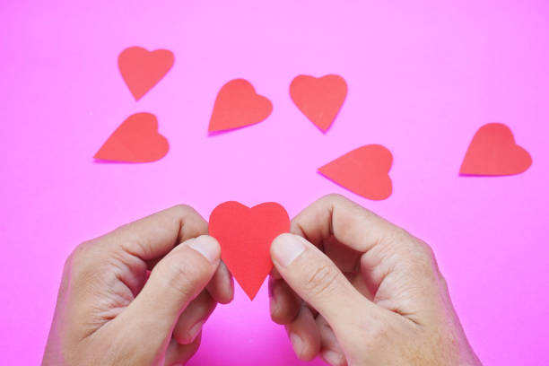 istock hand holding a heart shape on pink background 1455701938