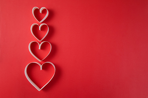 Heart shaped papers on red background with copy space