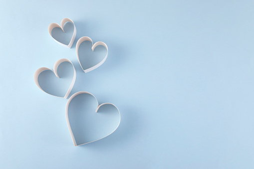 Heart shaped papers on blue background with copy space