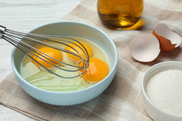 istock Whisking eggs in bowl on white wooden table, closeup 1455706792