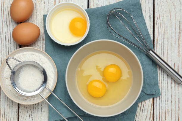 istock Whisk, eggs in bowl and flour on white wooden table, flat lay 1455706839
