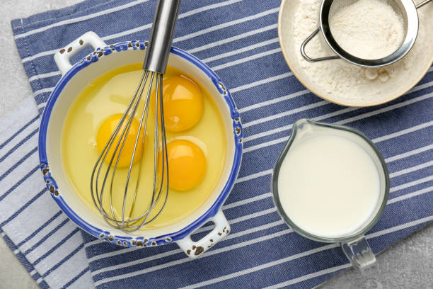 istock Whisk, eggs, milk and flour on grey table, flat lay 1455706948
