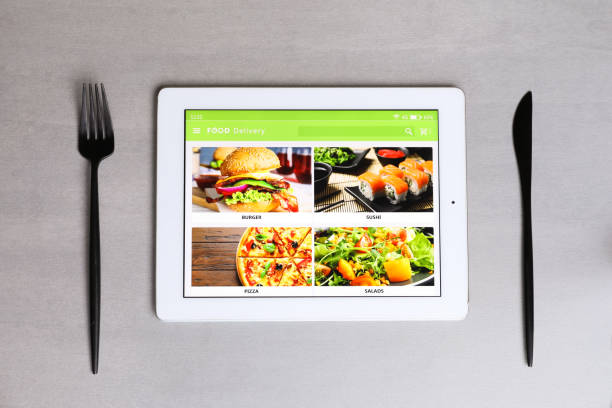 istock Modern tablet with open page for online food ordering and cutlery on grey table, flat lay. Concept of delivery service 1455707737