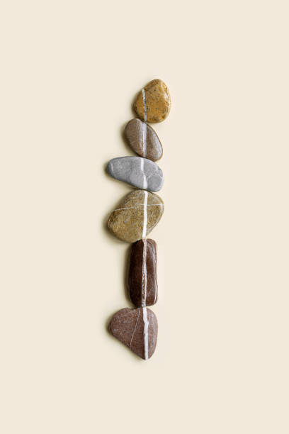istock Aesthetic minimal flat lay sea pebble stones with white line, beige background. Composition from natural colored stone on the same level. Balance or harmony concept, vertical row rocks. 1455708152