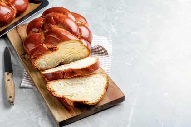 Cut homemade braided bread on grey table, space for text. Traditional Shabbat challah