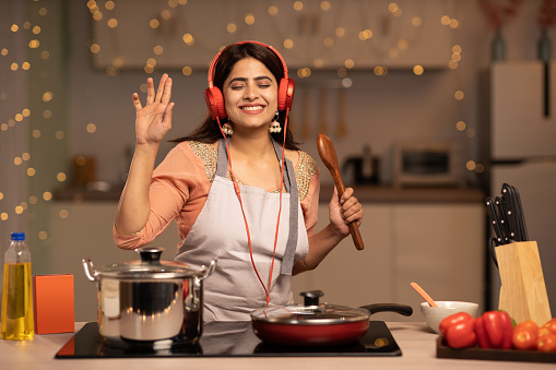 Young woman listening music while cooking at home