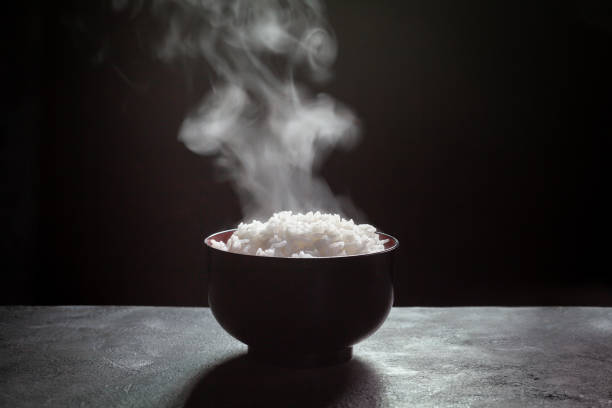 Cooked rice with steam in black bowl on dark background,hot cooked rice in bowl selective focus,hot food and healthy Cooked rice with steam in black bowl on dark background,hot cooked rice in bowl selective focus,hot food and healthy steamed stock pictures, royalty-free photos & images