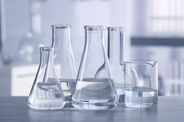 istock Different laboratory glassware with transparent liquid on wooden table against blurred background 1455710299